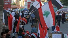A Baghdad street vendor sells flags of Iraq and Lebanon, both gripped by anti-government protests