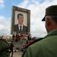 Protesters hold a national flag under a portrait of Syrian President Bashar al-Assad in the Syrian Golan Heights, during a demonstration on March 26, 2019
