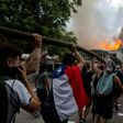 Demonstrators hold up a hose as flames engulf the Pedro de Valdivia University following a protest against the government of Chilean President Sebastian Pinera in Santiago, on November 8, 2019.Unrest began in Chile last October 18 with protests against...