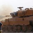 Turkish soldiers at a position east of Ras al-Ain watch as a tank fires on positions held by Kurdish-led forces