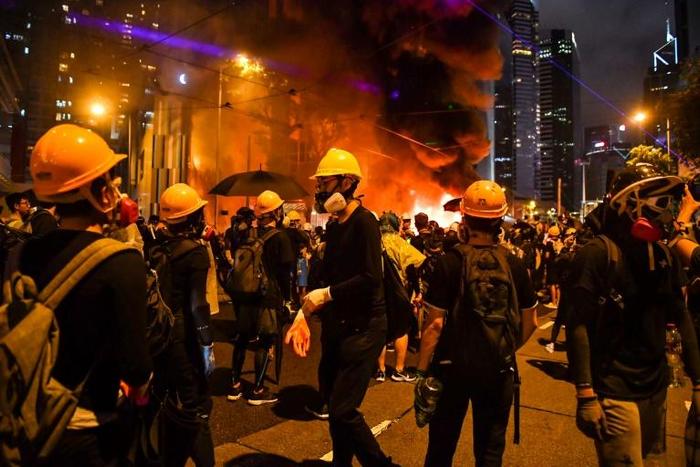 Thick, black smoke swirled from a large fire started by masked Hong Kong protesters at a barricade on a major thoroughfare