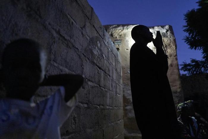 Issa Haidari, who shelters people displaced by violence in Mali, prays after nightfall in the garden at his home in Segou