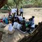 Twenty Yemeni pupils listen to their teacher with textbooks balanced in their laps as they sit under trees in their southern village, where the school building remains unfinished