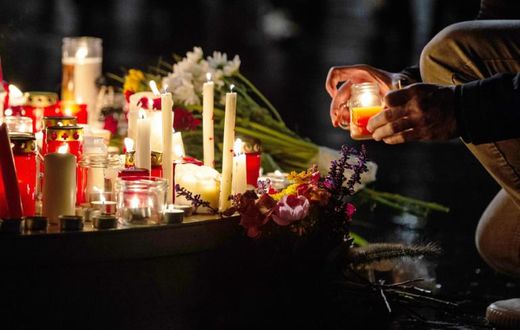 People leave candles and flowers at a vigil at the Marktplatz in Halle, eastern Germany