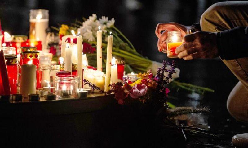 People leave candles and flowers at a vigil at the Marktplatz in Halle, eastern Germany