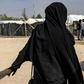 A French woman held at Al-Hol camp holds a child by the hand
