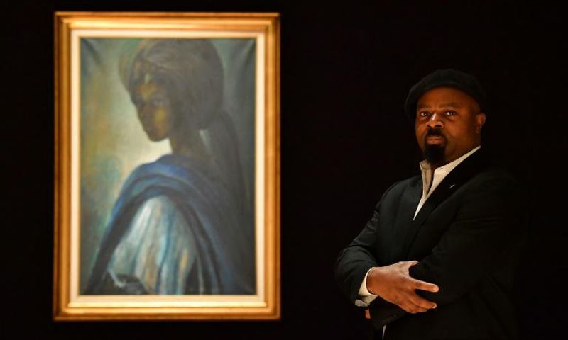 Nigerian author Ben Okri poses last year with Ben Enwonwu's 'Tutu' known as the 'African Mona Lisa'