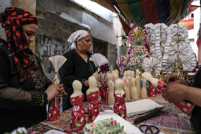 Egyptian women decorate traditional sugar statuettes in the capital Cairo for Al Mawlid Al Nabawi celebrations
