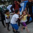 Migrants shield their mouths from tear gas during clashes at the Moira refugee camp