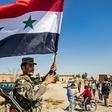 A Syrian regime soldier waves the national flag in the town of Tal Tamr as Damascus deploys forces towards the Turkish border