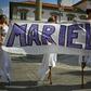 Women walk on stilts while holding a banner in memory of Rio councillor Marielle Franco, at the location in Rio de Janeiro where she was shot dead