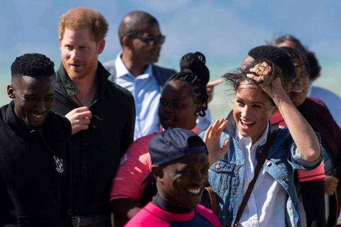 Wind and smiles: Prince Harry and his wife Meghan meet members of Waves for Change. The group uses surfing to help young people trapped in Cape Town's slums get a different perspective on life