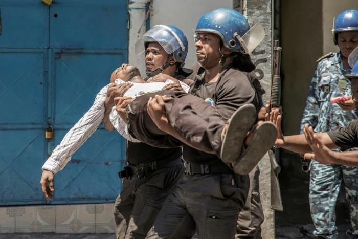 Police take away a plainclothes policeman injured in Monday's clashes