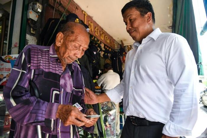 Puea Thai’s party candidate Chadchart Sittipunt talks to a voter in Bangkok