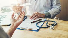 Doctor or physician writing diagnosis and giving a medical prescription to female Patient