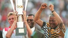 Then South Africa president Nelson Mandela (R) celebrates as captain Neil Tovey (L) holds the Africa Cup of Nations trophy after defeating Tunisia in the 1996 final