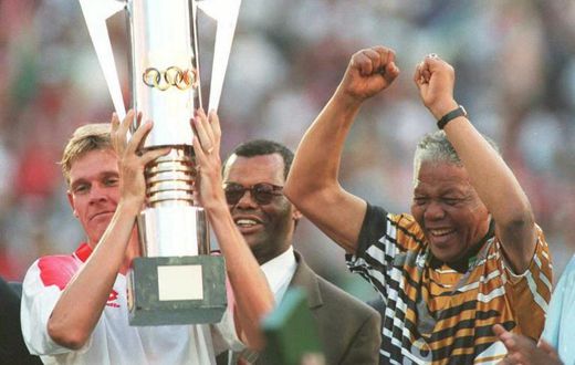 Then South Africa president Nelson Mandela (R) celebrates as captain Neil Tovey (L) holds the Africa Cup of Nations trophy after defeating Tunisia in the 1996 final