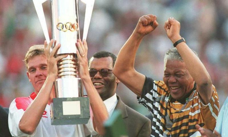 Then South Africa president Nelson Mandela (R) celebrates as captain Neil Tovey (L) holds the Africa Cup of Nations trophy after defeating Tunisia in the 1996 final