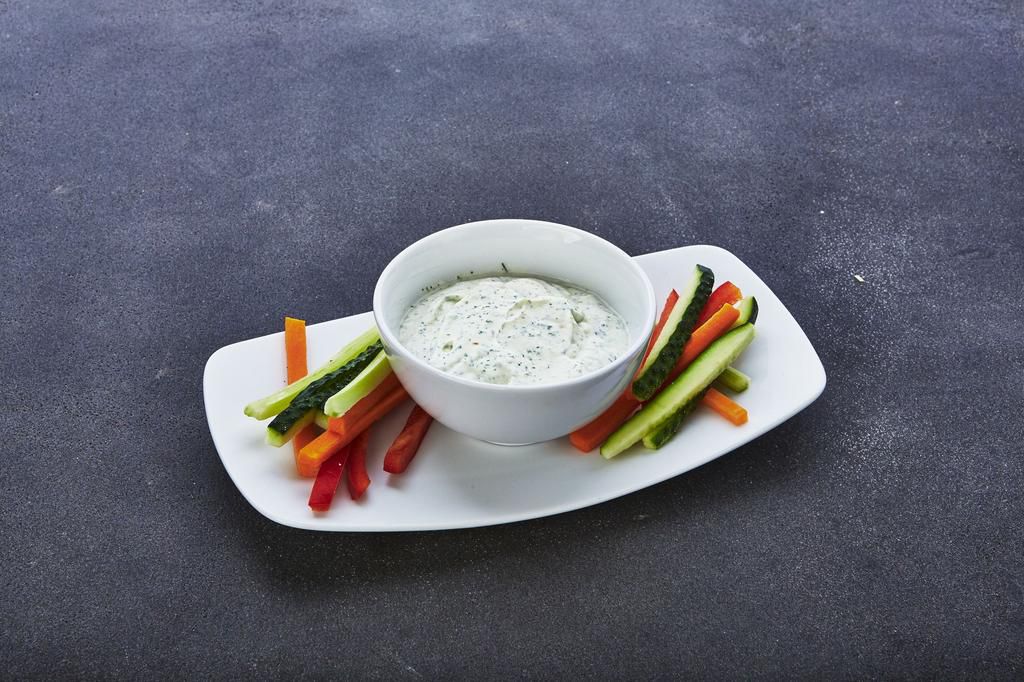 Vegetable assortment and sauce with feta cheese on a wooden background, close-up
