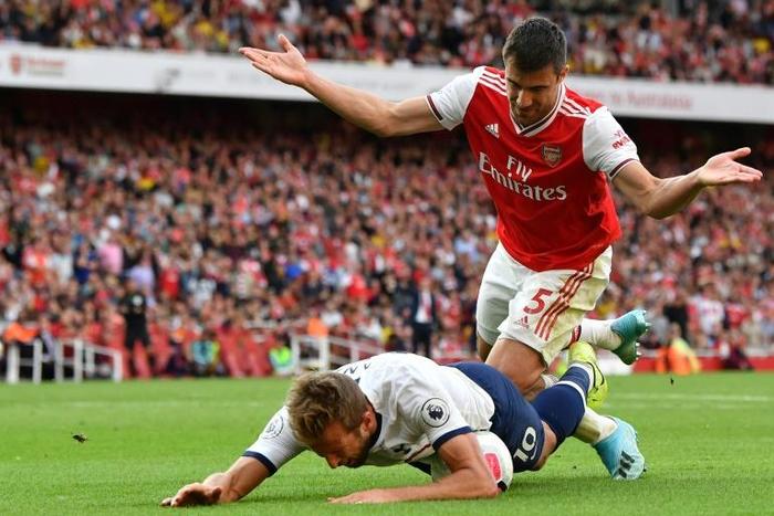 Tottenham striker Harry Kane falls in the area under pressure from Arsenal's Sokratis