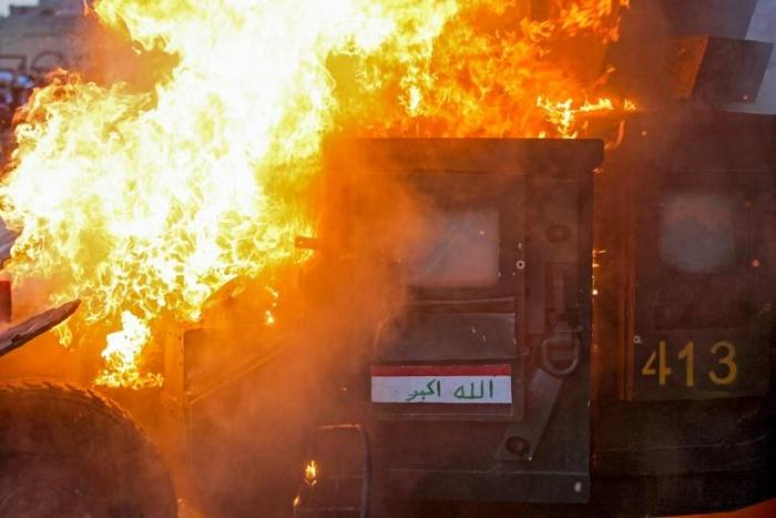 A riot police vehicle burns in Tayeran Square in the heart of Baghdad on Thursday as protests escalate in the capital and across the south