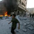 A young boy runs past a fire started in a building following a reported airstrike by Syrian regime forces in the town of Maaret al-Noman in Syria's northwestern Idlib province on August 28, 2019