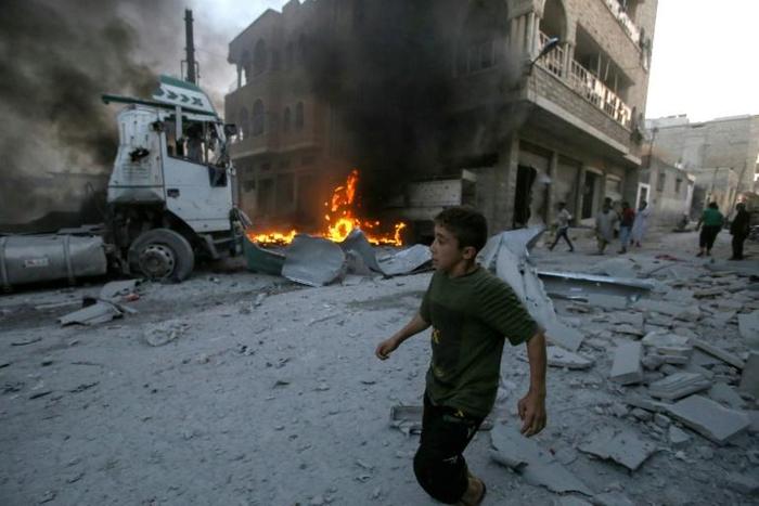 A young boy runs past a fire started in a building following a reported airstrike by Syrian regime forces in the town of Maaret al-Noman in Syria's northwestern Idlib province on August 28, 2019