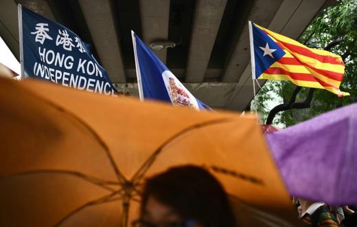 A flag that reads "Hong Kong Independence" is seen alongside the territory's British colonial-era flag and the pro-independence 'Estelada' Catalan flag during a march in Hong Kong on China's national day