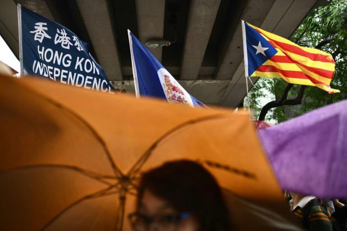 A flag that reads "Hong Kong Independence" is seen alongside the territory's British colonial-era flag and the pro-independence 'Estelada' Catalan flag during a march in Hong Kong on China's national day
