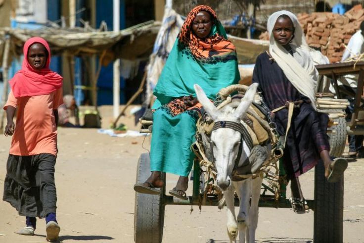 Displaced Sudanese women ride on a donkey cart to move around the Abu Shouk camp, north of El-Fasher, the capital of North Darfur state