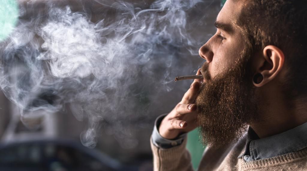 Close up of a young hipster smoking cigarette.