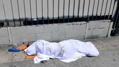 A homeless person' sleeping under a sheet on a sidewalk in Los Angeles, California on August 22, 2019, home to one of the nation's largest homeless populations