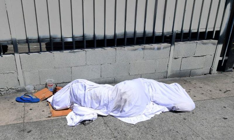 A homeless person' sleeping under a sheet on a sidewalk in Los Angeles, California on August 22, 2019, home to one of the nation's largest homeless populations