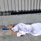 A homeless person' sleeping under a sheet on a sidewalk in Los Angeles, California on August 22, 2019, home to one of the nation's largest homeless populations