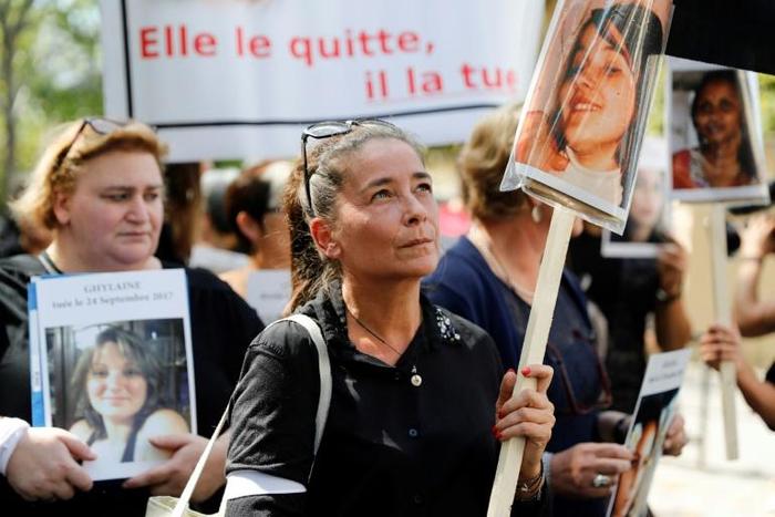 A woman holds the picture of a victim as she takes part in a protest march denouncing violence against women in Paris