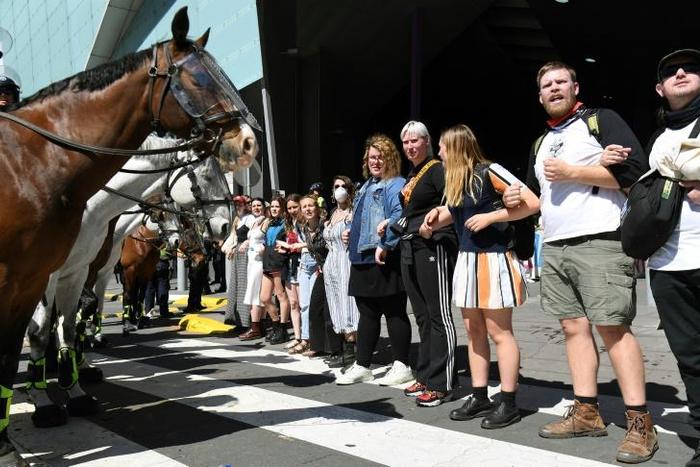 Climate change protesters attempting to blockade a mining conference linked arms in front of mounted police in Melbourne before clashes started
