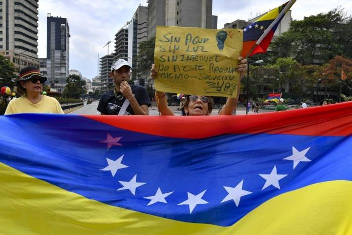 Opposition supporters demonstrate behind a Venezuelan national flag in the neighborhood of Los Palos Grandes in Caracas, on March 31, 2019
