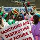 Demonstrators chant slogans and wave Zimbabwe's national flag during a rally to denounce US and EU economic sanctions