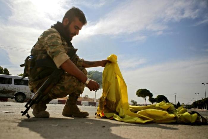 A Turkish-backed Syrian fighter burns the flag of the Kurd-led SDF