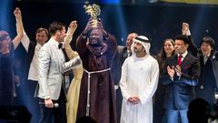 This picture provided on March 24, 2019 by the Global Education and Skills Forum of the Varkey Foundation, shows Kenyan teacher Peter Tabichi (C) in Dubai holding up the trophy for world's best teacher which comes with a prize of $1 million