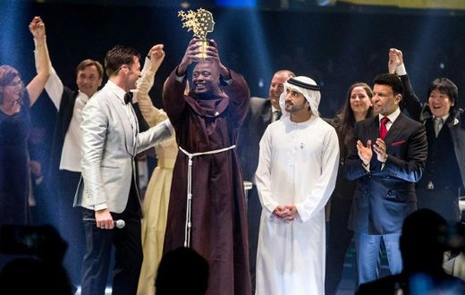This picture provided on March 24, 2019 by the Global Education and Skills Forum of the Varkey Foundation, shows Kenyan teacher Peter Tabichi (C) in Dubai holding up the trophy for world's best teacher which comes with a prize of $1 million