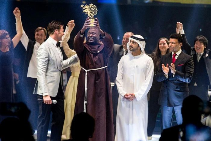 This picture provided on March 24, 2019 by the Global Education and Skills Forum of the Varkey Foundation, shows Kenyan teacher Peter Tabichi (C) in Dubai holding up the trophy for world's best teacher which comes with a prize of $1 million