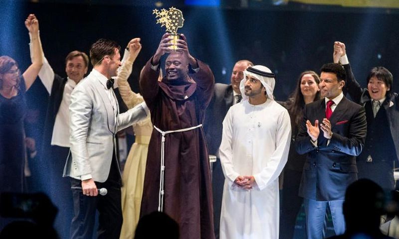 This picture provided on March 24, 2019 by the Global Education and Skills Forum of the Varkey Foundation, shows Kenyan teacher Peter Tabichi (C) in Dubai holding up the trophy for world's best teacher which comes with a prize of $1 million