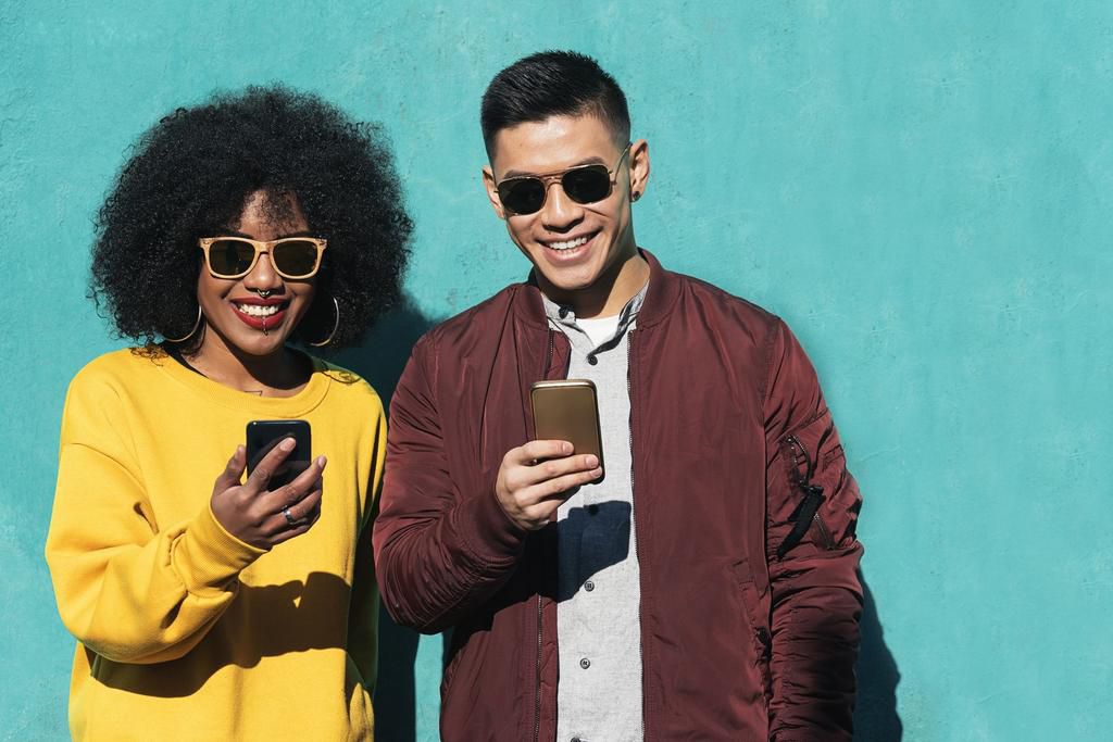 Two happy friends using the mobile in the street.