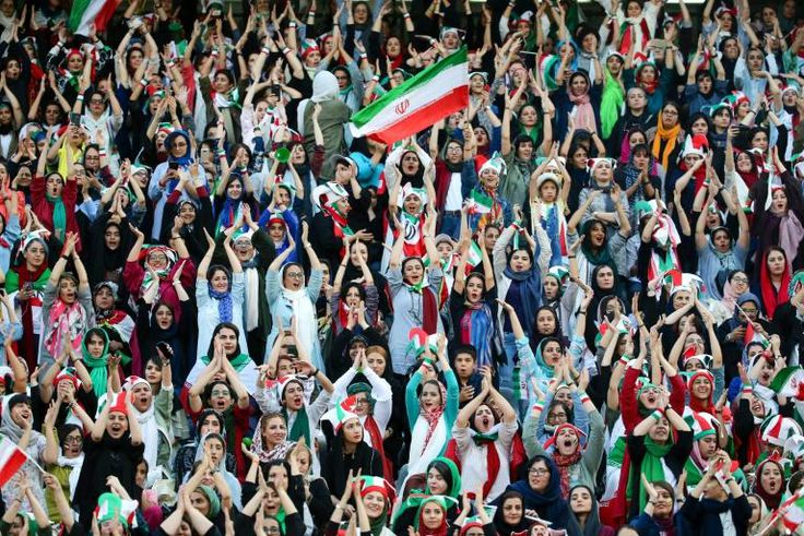 Wearing sporty hats and the national flag, Iranian women cheer for their team at a game they will never forget.