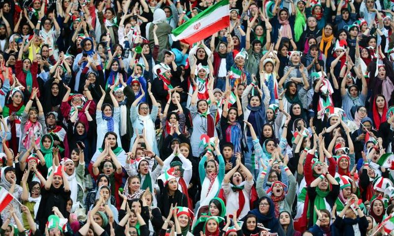 Wearing sporty hats and the national flag, Iranian women cheer for their team at a game they will never forget.