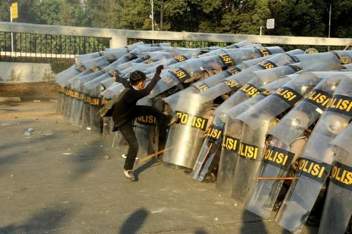 A protester attacks a police line during a demonstration in Jakarta
