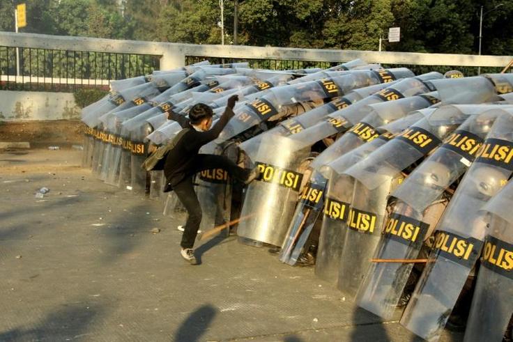 A protester attacks a police line during a demonstration in Jakarta
