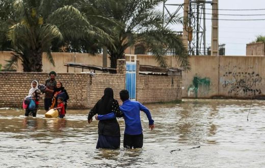An Iranian family walks through a flooded street in a village around the city of Ahvaz