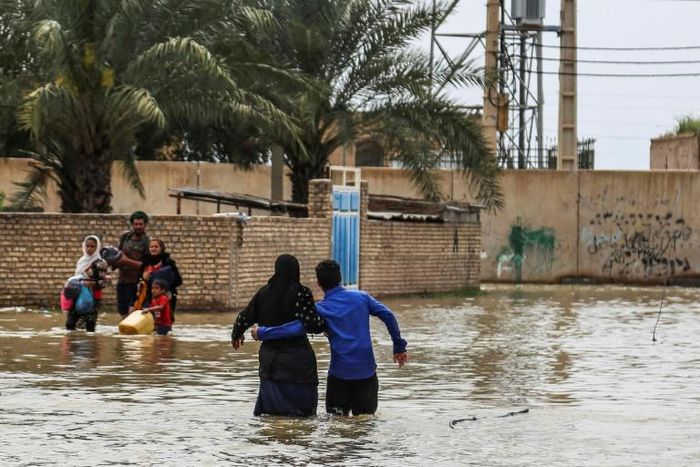 An Iranian family walks through a flooded street in a village around the city of Ahvaz